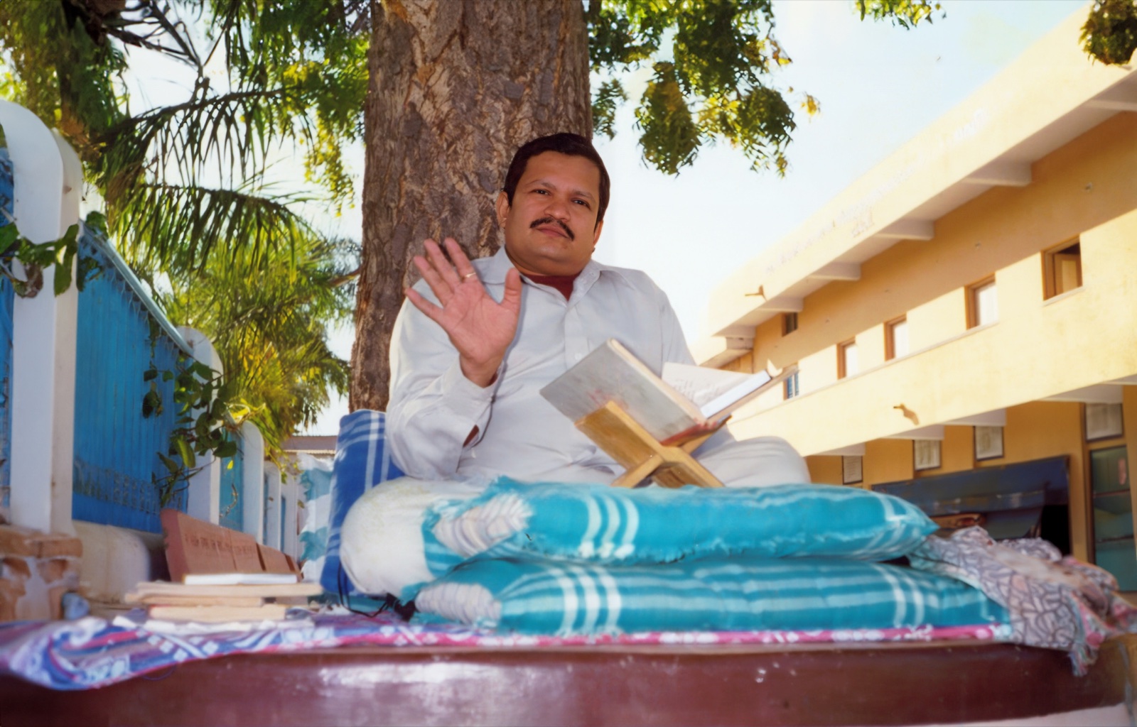 Shri Devchand bhai Shah teaching outdoors, a book open on a stand